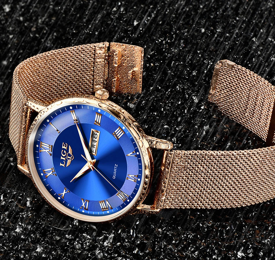 Elegant rose gold mesh bracelet watch with a round blue dial, gold Roman numerals, and a day-date display.