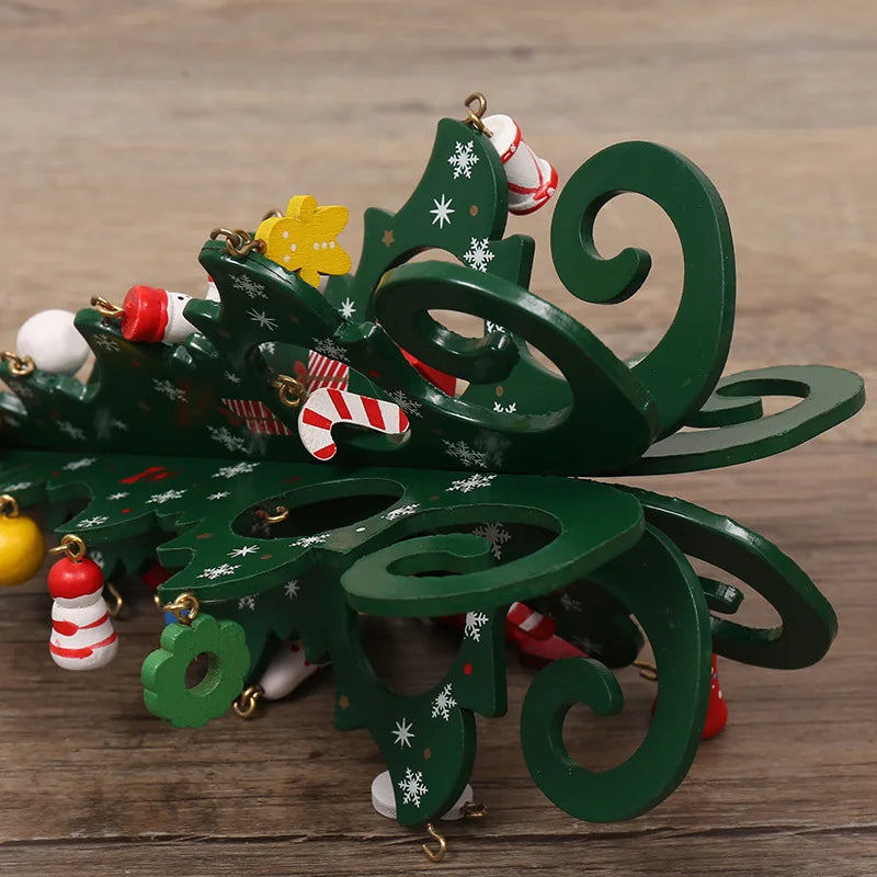 A decorative green wooden Christmas tree ornament with intricate scroll cut-outs, white snowflakes and hanging charms.
