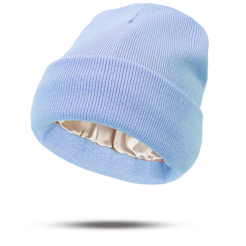 Light blue knitted beanie hat with a smooth, champagne-coloured satin lining.
