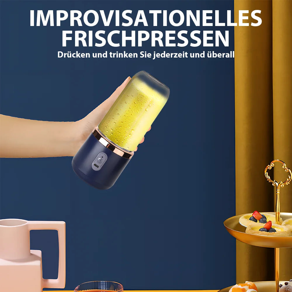 Handheld portable blender in navy blue with a rose-gold rim, filled with yellow juice, held against a blue background.
