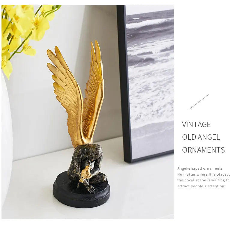 Vintage-style ornament of a kneeling figure with large golden wings, holding a small bird on a black circular base.