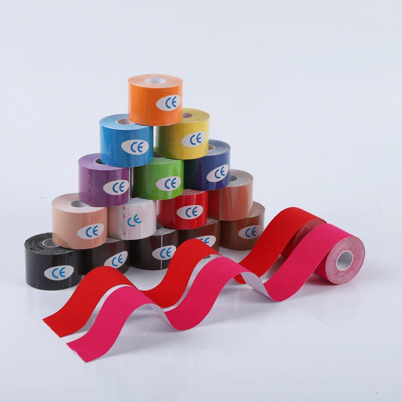 A pyramid stack of assorted colourful kinesiology sports tape rolls, with two red and pink strips unrolled in front.