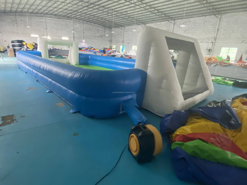 Inflatable blue and white football pitch with integrated goals and an external air blower.