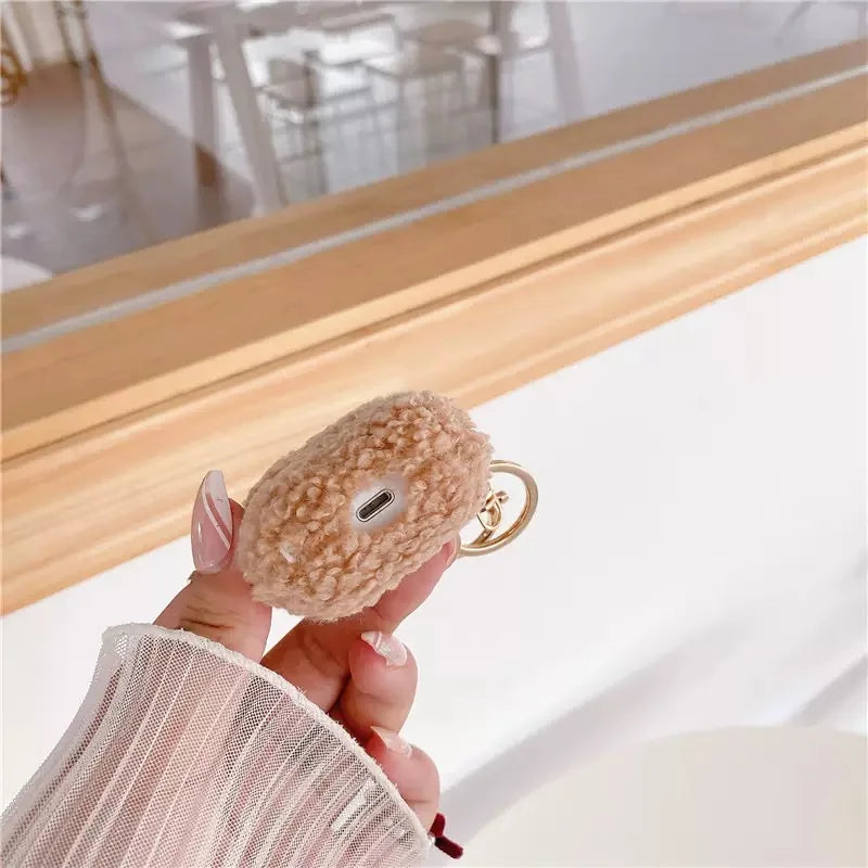 Fluffy beige fleece protective case for AirPods with a gold-tone keyring attachment.