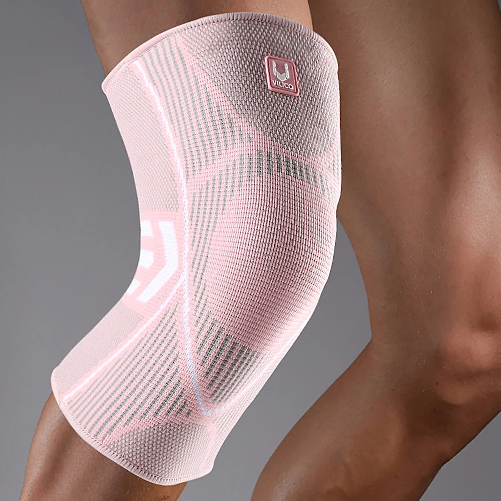 Pink compression knee support sleeve with white athletic patterns and a Vilico logo on a person's leg.