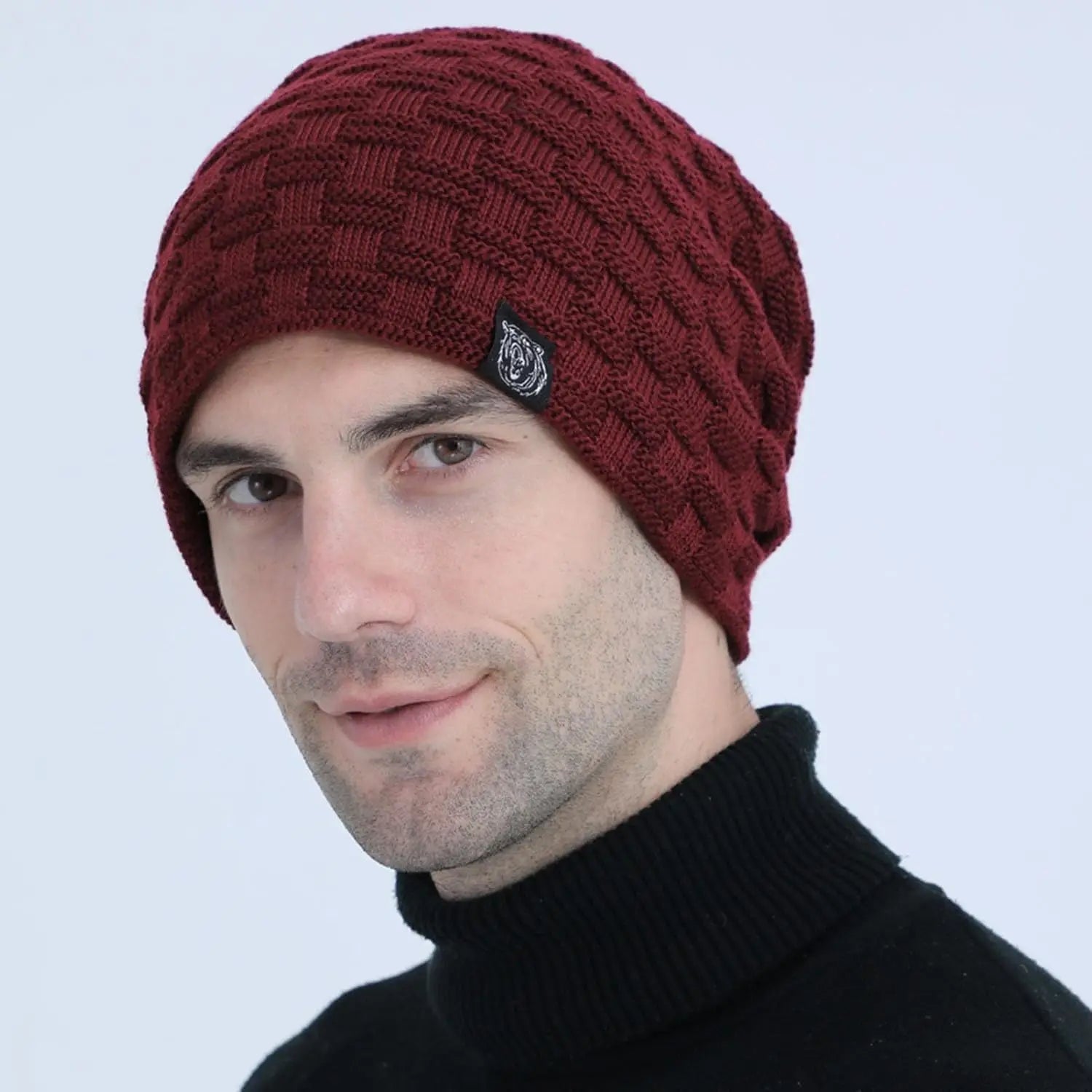 A man wearing a burgundy, chunky knit, plush-lined winter beanie with a subtle textured square pattern.