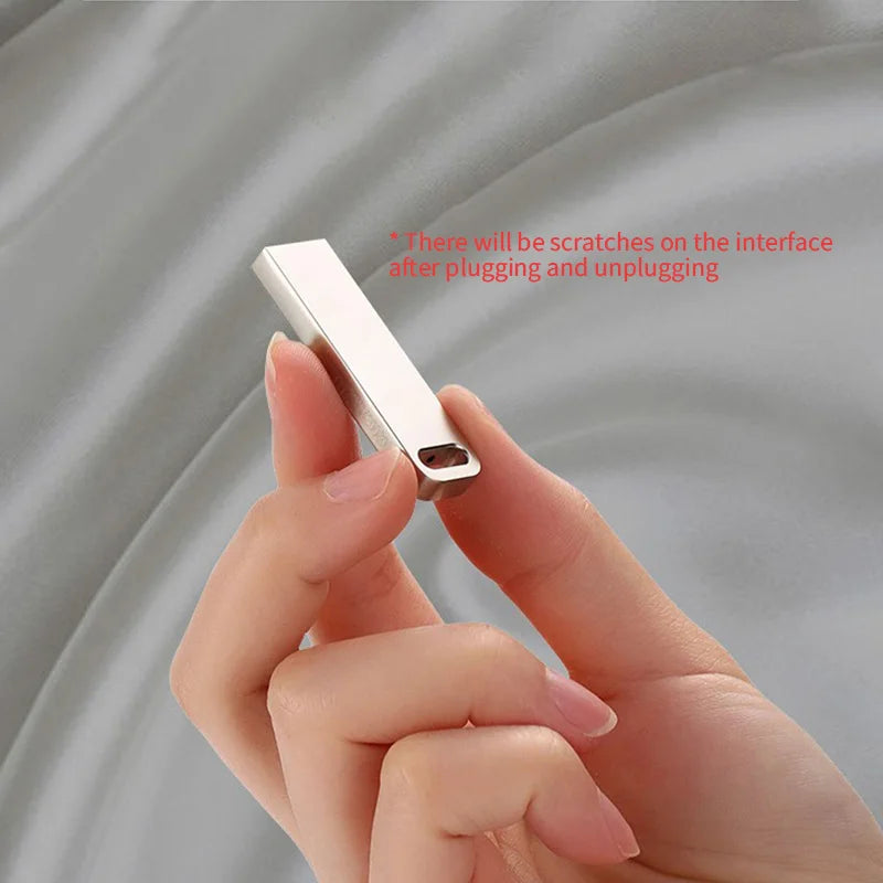 Sleek, silver metal USB flash drive with a slim, minimalist design being held between thumb and forefinger.