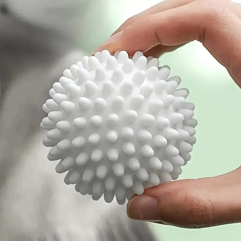 A hand holding a white, spiky, textured sensory massage ball.