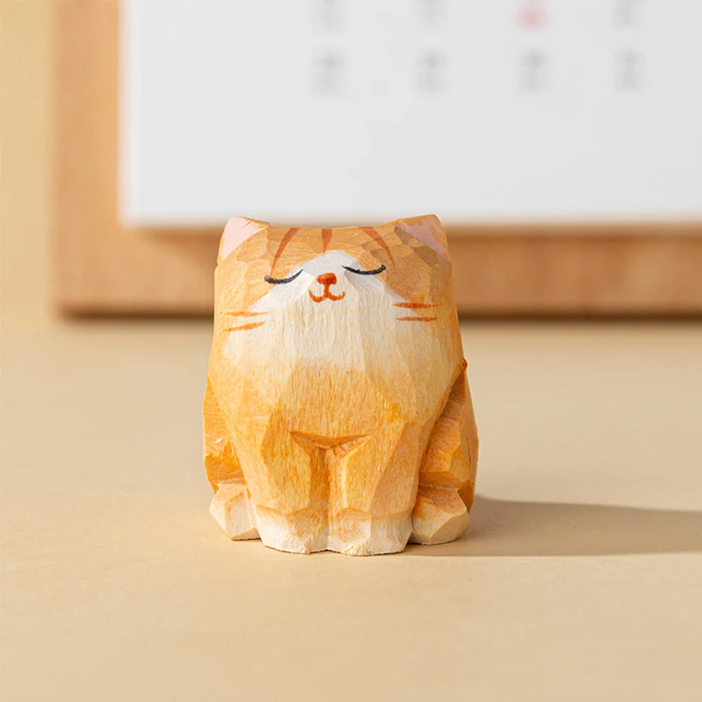 Small, hand-carved wooden figurine of a sitting ginger tabby cat with a peaceful, closed-eye expression.