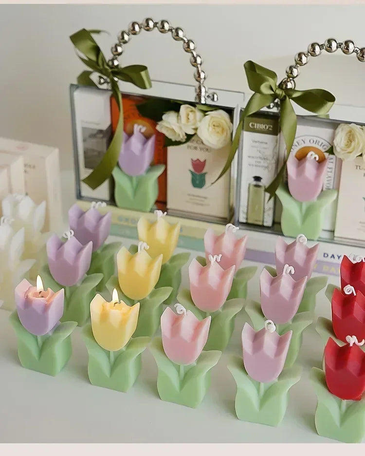 Assorted pastel tulip-shaped candles with green leaves, displayed alongside decorative gift sets with sage green ribbons.