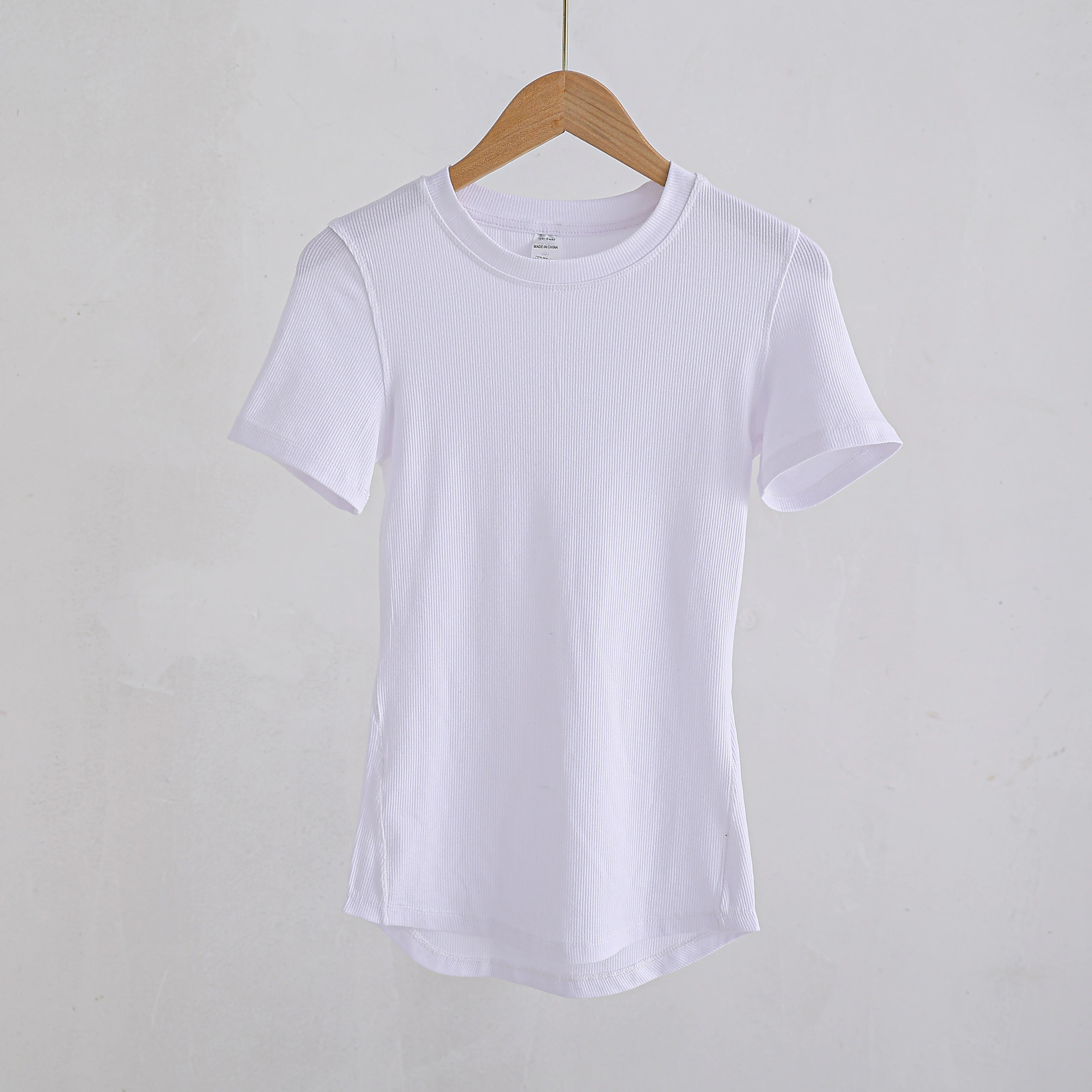 White ribbed t-shirt with a crew neck and short sleeves, hanging on a wooden hanger against a plain white background.