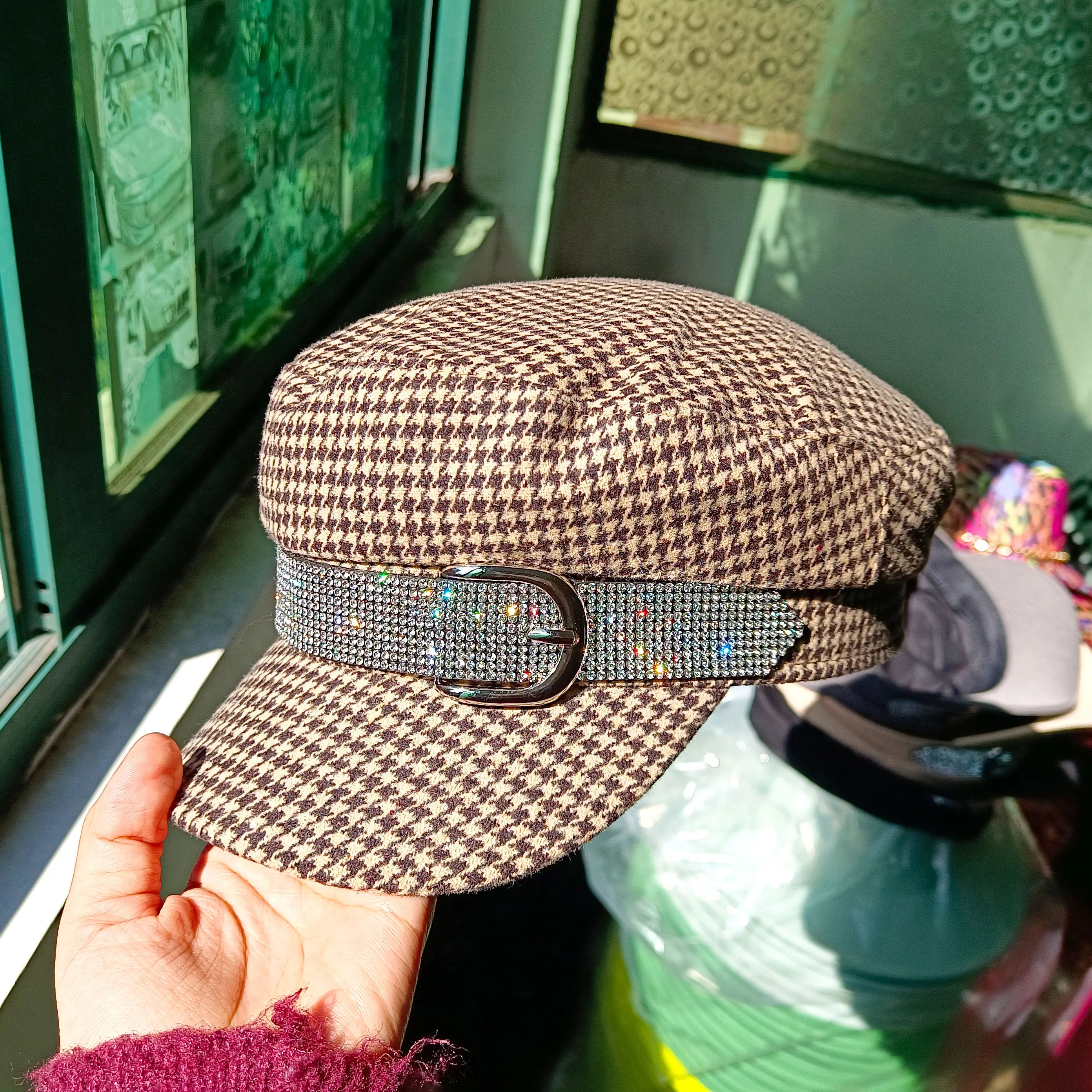 Brown and beige houndstooth baker boy cap featuring a sparkling rhinestone-embellished band with a silver buckle.