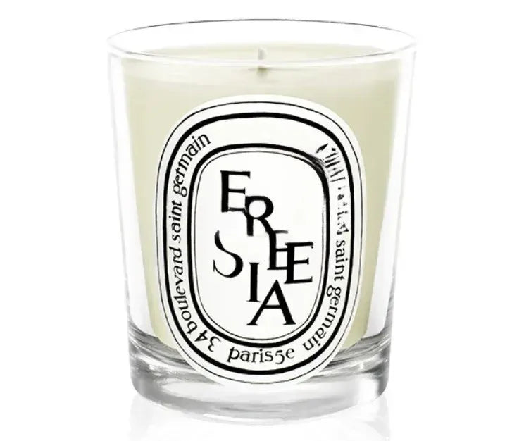 Scented candle in a clear glass jar with a white oval label featuring black decorative typography.