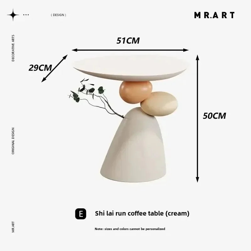 Minimalist cream-coloured side table featuring an abstract, pebble-like sculptural base and a smooth round tabletop.