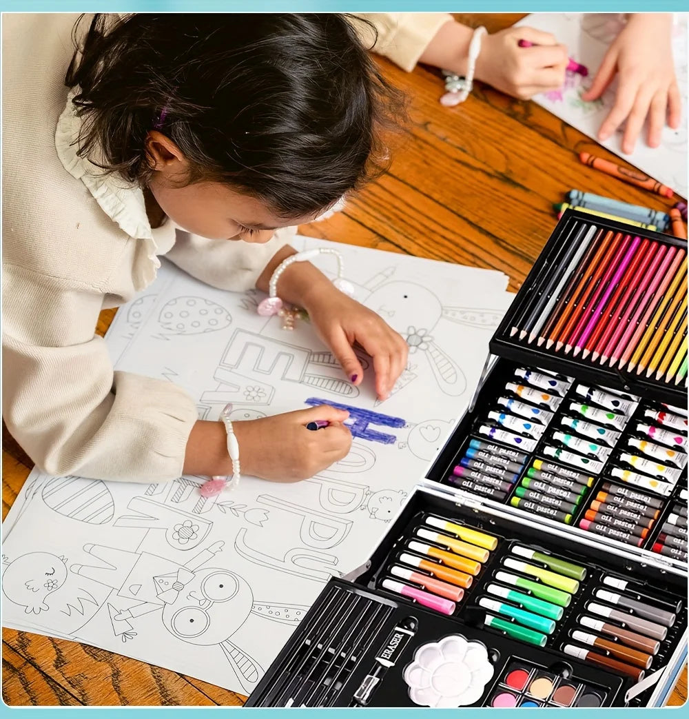 Child coloring on paper with a large, multi-tier art case filled with colourful pencils, oil pastels, and paints.