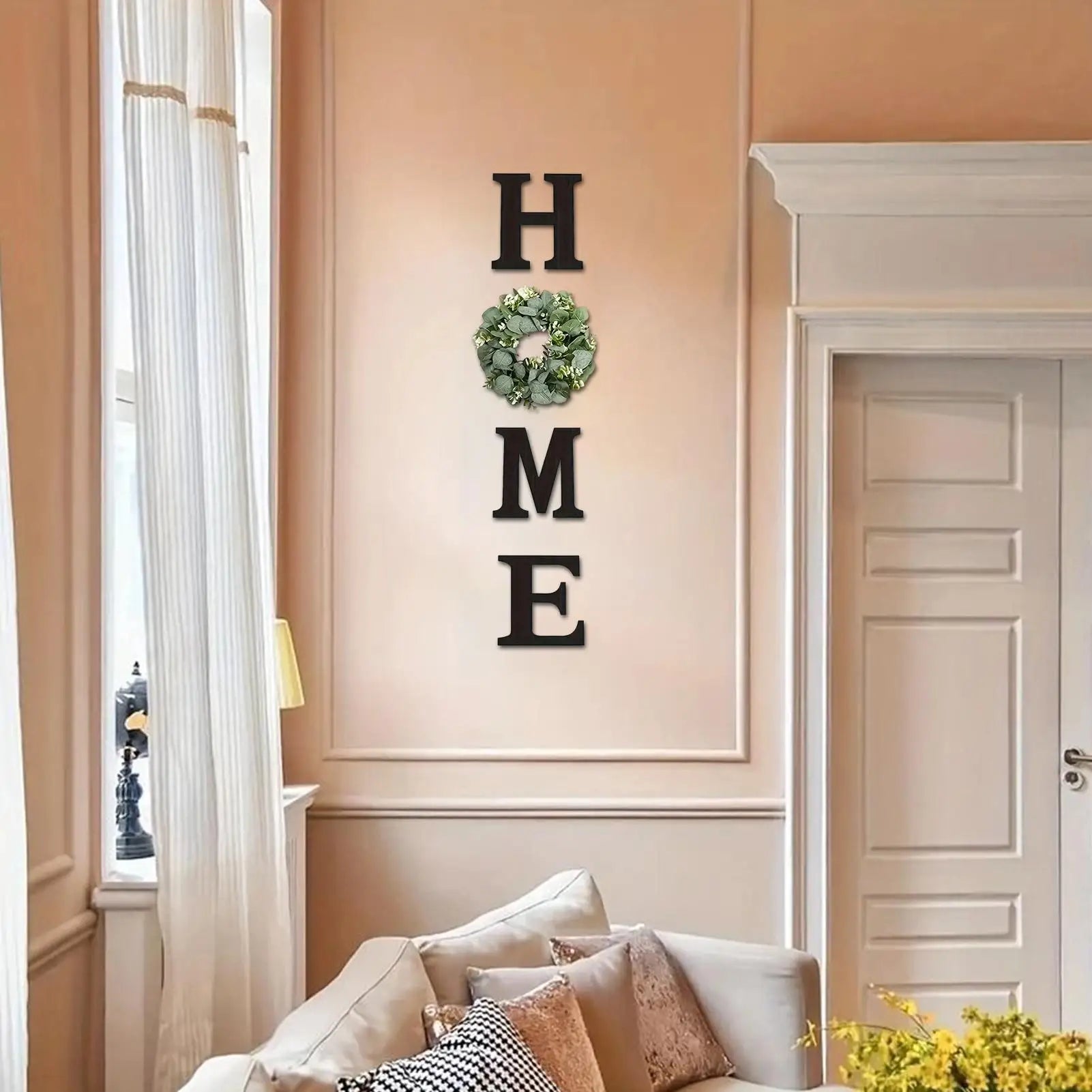 Vertical black wooden "HOME" wall sign featuring a green artificial eucalyptus wreath in place of the letter "O".