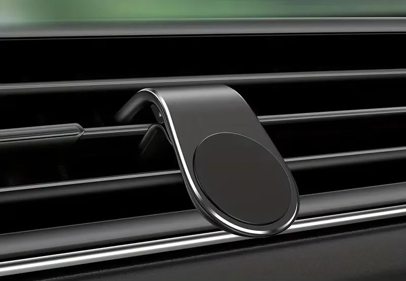 Matte black magnetic car phone mount attached to a vehicle's air vent. Sleek, minimalist curved design.