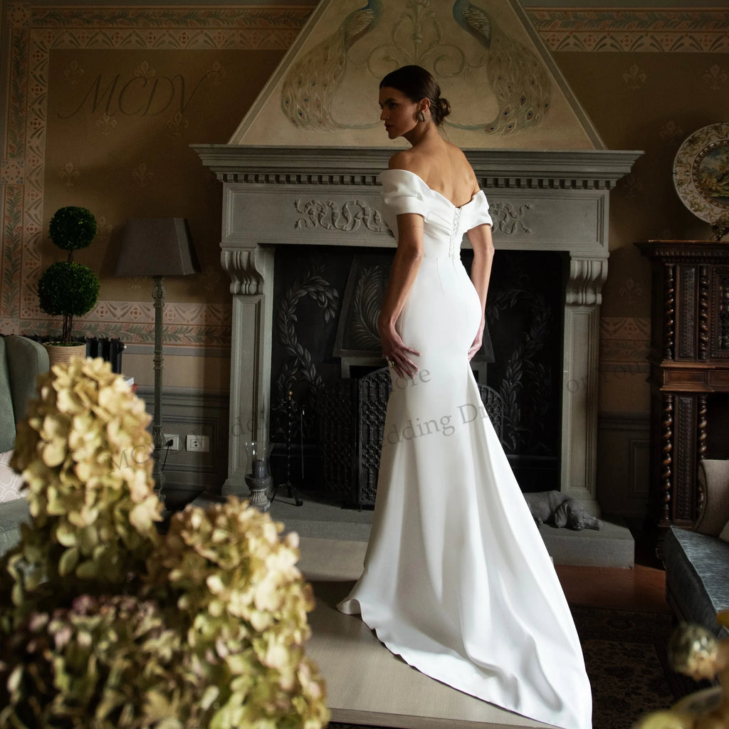 White off-shoulder satin mermaid wedding dress with sweetheart neckline and fitted silhouette.