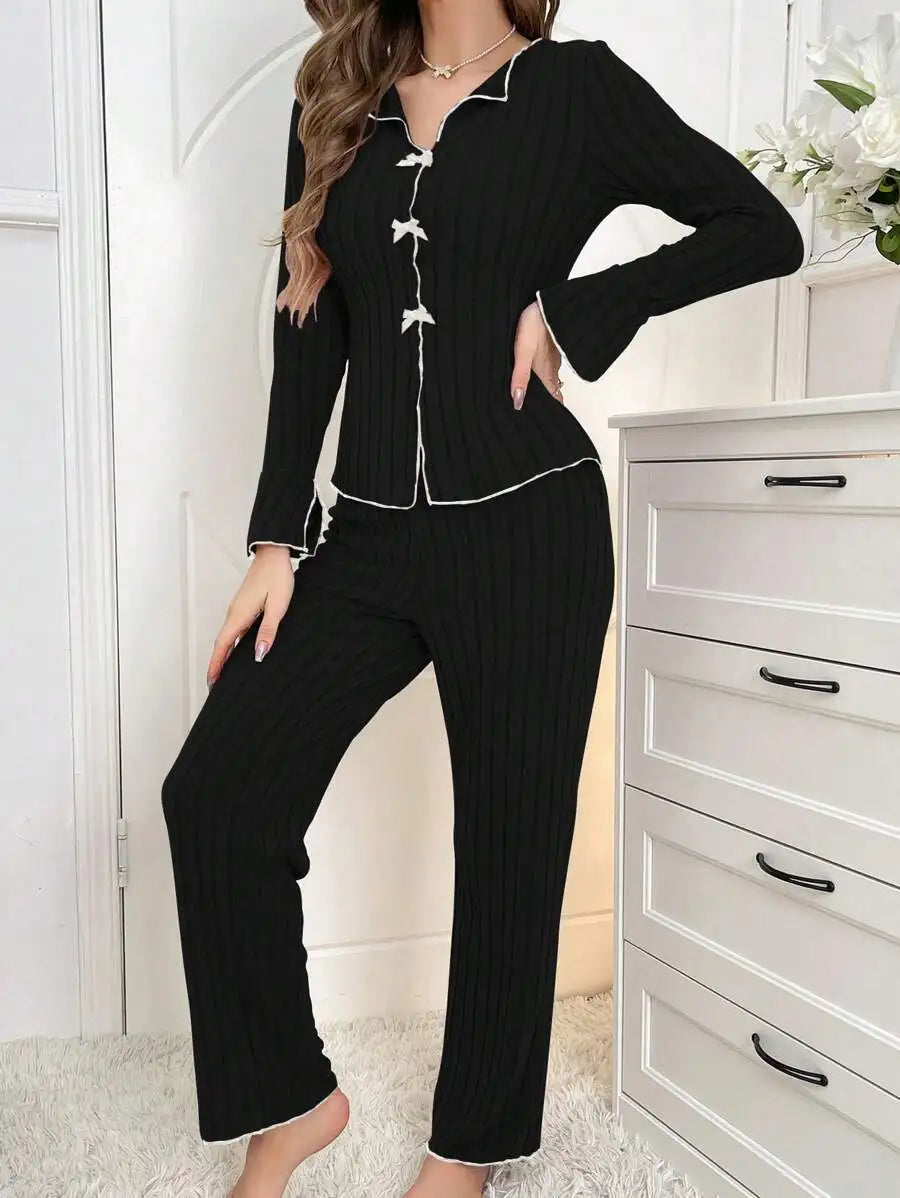 Black ribbed loungewear set with white contrast piping, button-down top, and long trousers.
