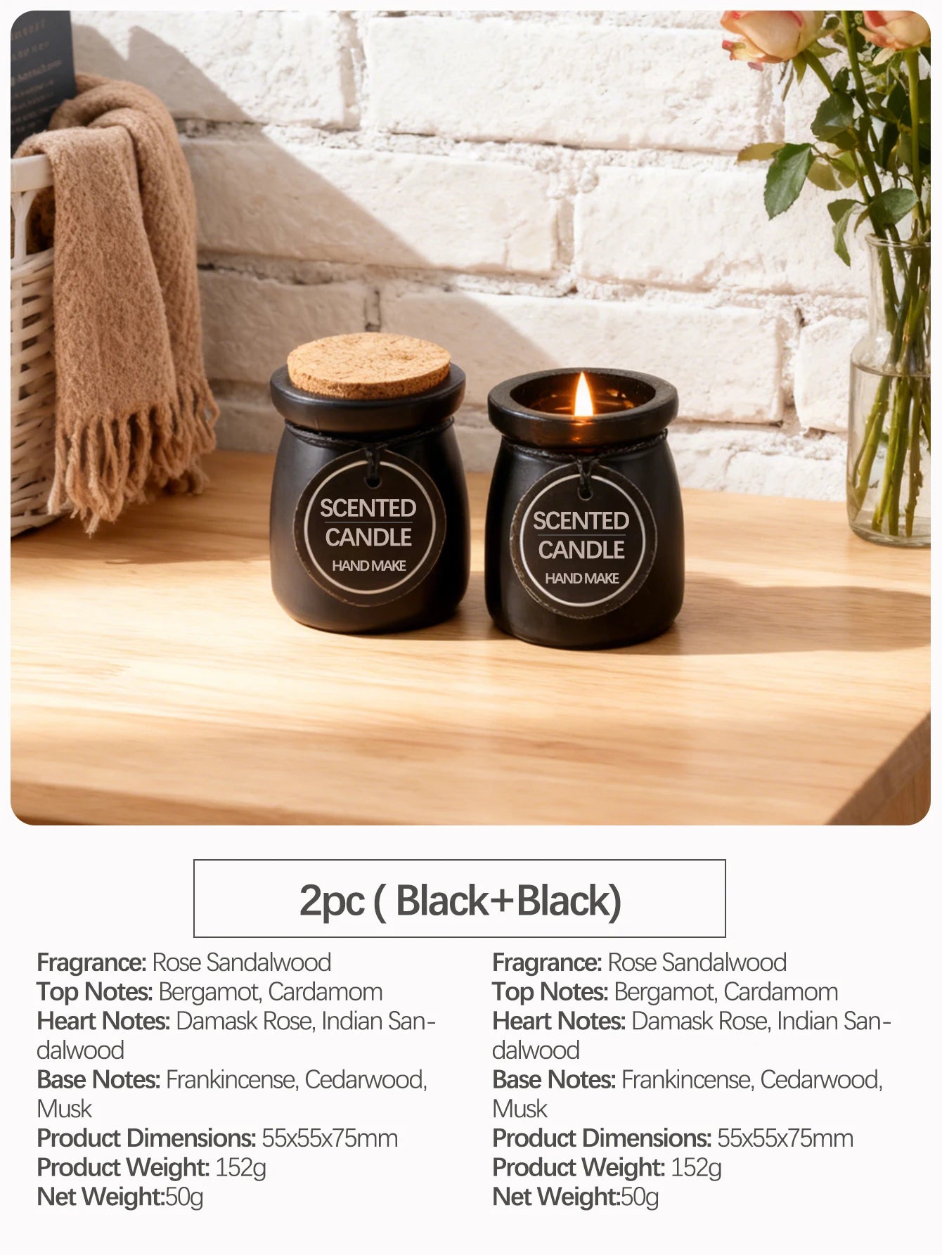 Two black handmade scented candles in jars with cork lids, one lit, set on a wooden table.