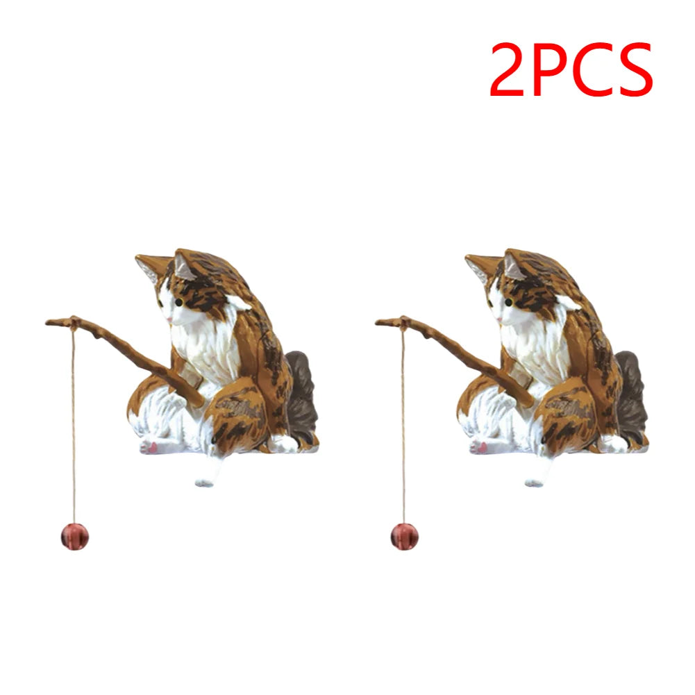 Two small, brown and white tabby cat ornaments for an aquarium, each holding a fishing rod with a hanging bauble.