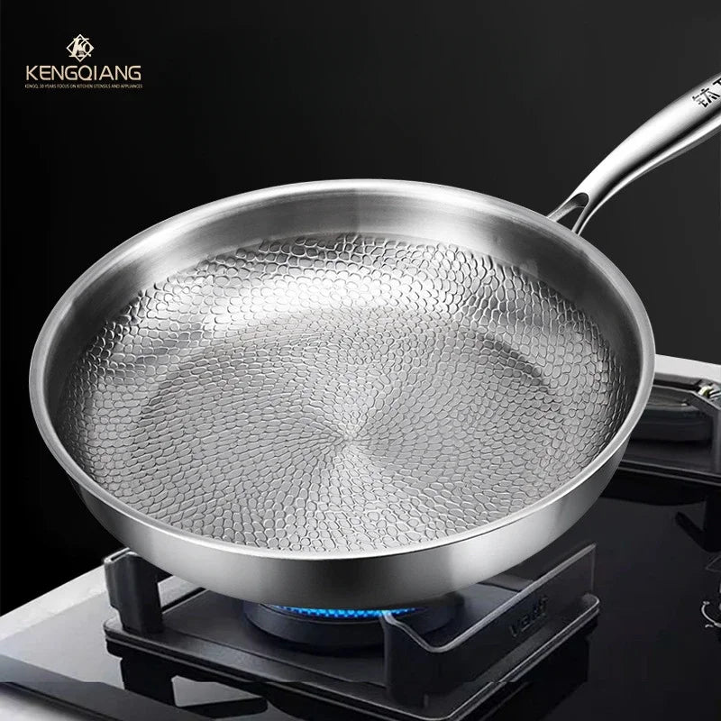 Stainless steel frying pan with a textured, honeycomb-patterned interior on a gas stove.