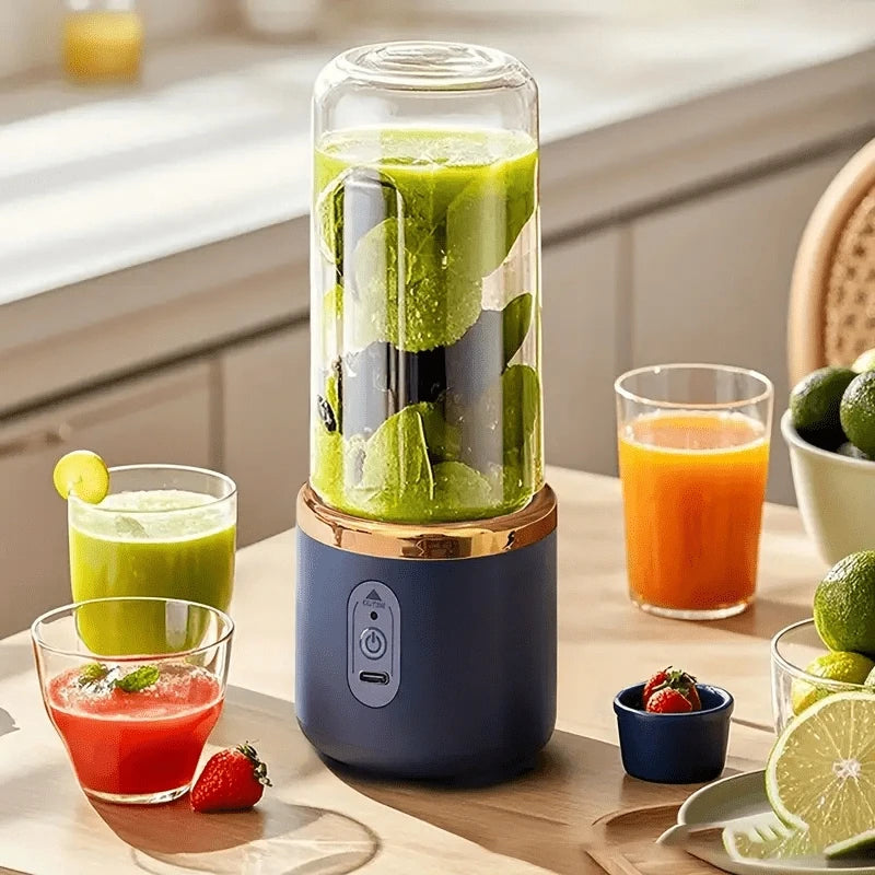 Portable navy blue personal blender with a clear glass cup and gold trim, on a kitchen table with fruit and juices.