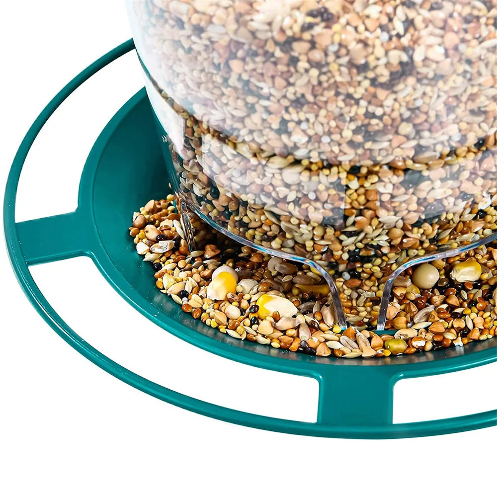 Clear plastic bird feeder filled with mixed seeds, featuring a round teal base and perch ring.