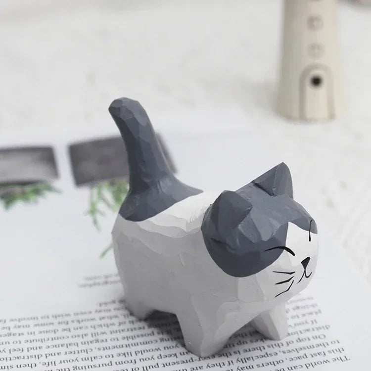 Small, hand-carved wooden cat ornament with grey and white faceted finish and a happy, smiling face.