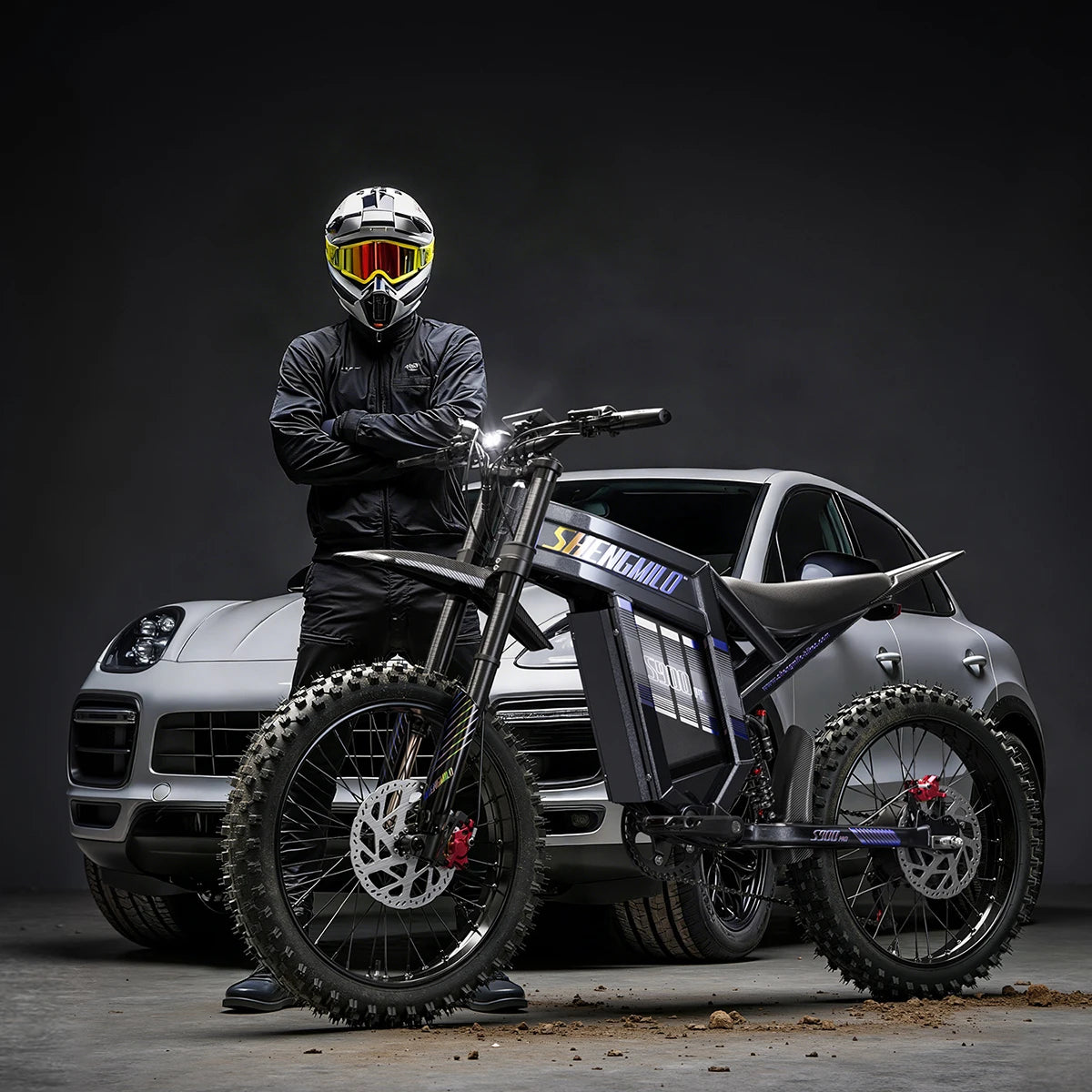Shengmilo S900 Pro black electric dirt bike with thick off-road tires, disc brakes, and a rider standing behind it.