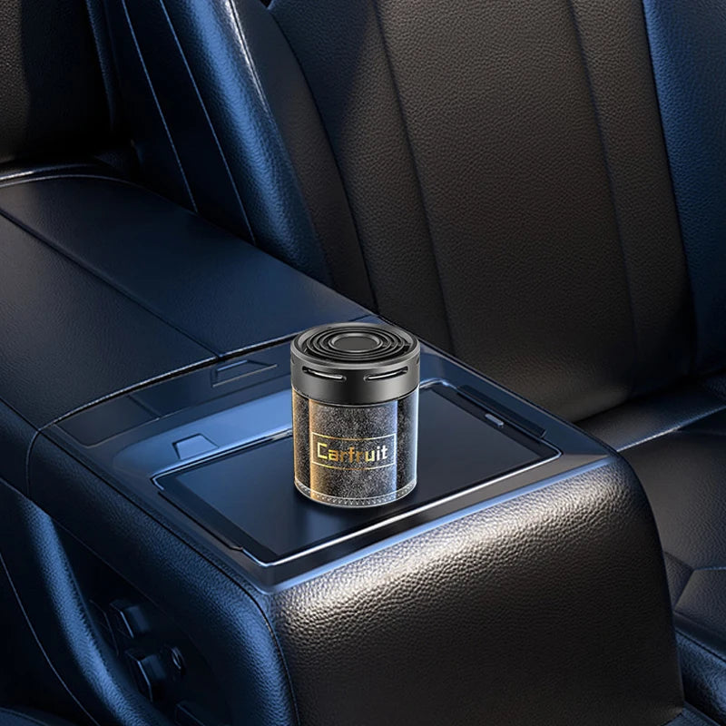 Black cylindrical car air freshener with a sleek, minimalist design resting on a dark leather car console.