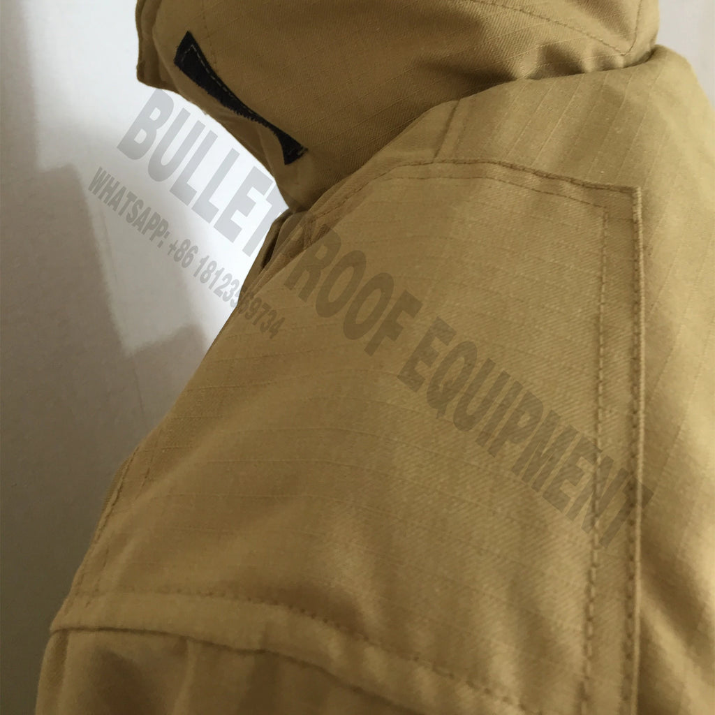 Close-up of a tan, ripstop fabric tactical jacket with a shoulder pocket and hood, against a light background.