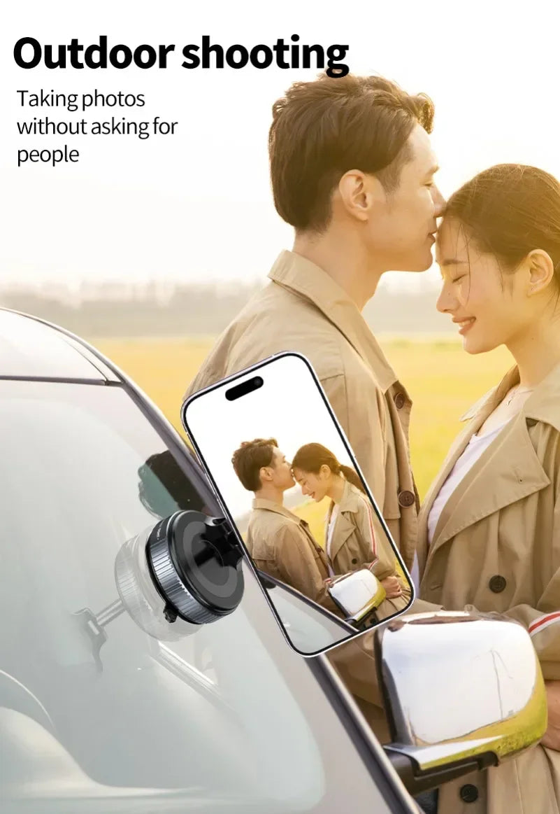 Black circular smartphone car mount attached to a windshield, holding a phone showing a couple outdoors.