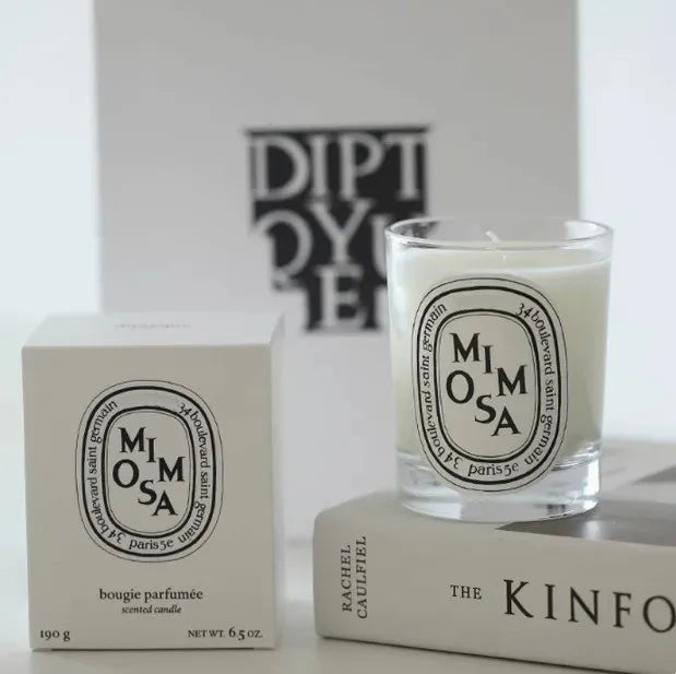 Mimosa scented candle in a clear glass jar with an oval label, shown alongside its matching white presentation box.