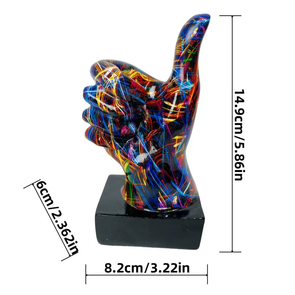 Decorative thumb-up hand sculpture with a multicoloured abstract paint splatter design on a black base. 14.9cm high.