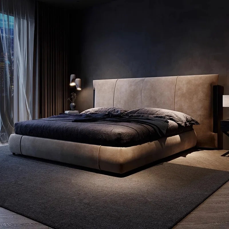 Minimalist upholstered bed in taupe fabric, featuring a tall, panelled headboard in a dark, modern bedroom setting.