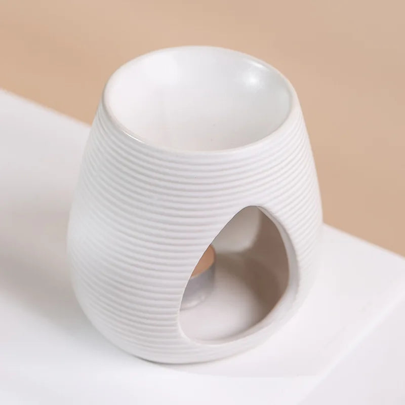 White ceramic oil burner with a ribbed texture and teardrop-shaped opening for a tealight candle.
