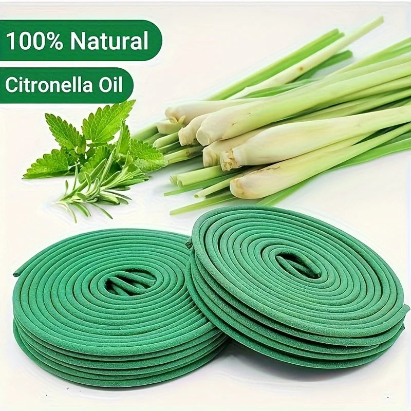 Green natural citronella oil mosquito coils stacked next to fresh lemongrass stalks and herbs.