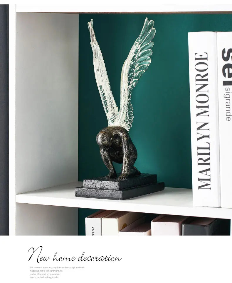 Sculpture of a kneeling figure in dark bronze with translucent, upward-stretched angel wings on a square black base.