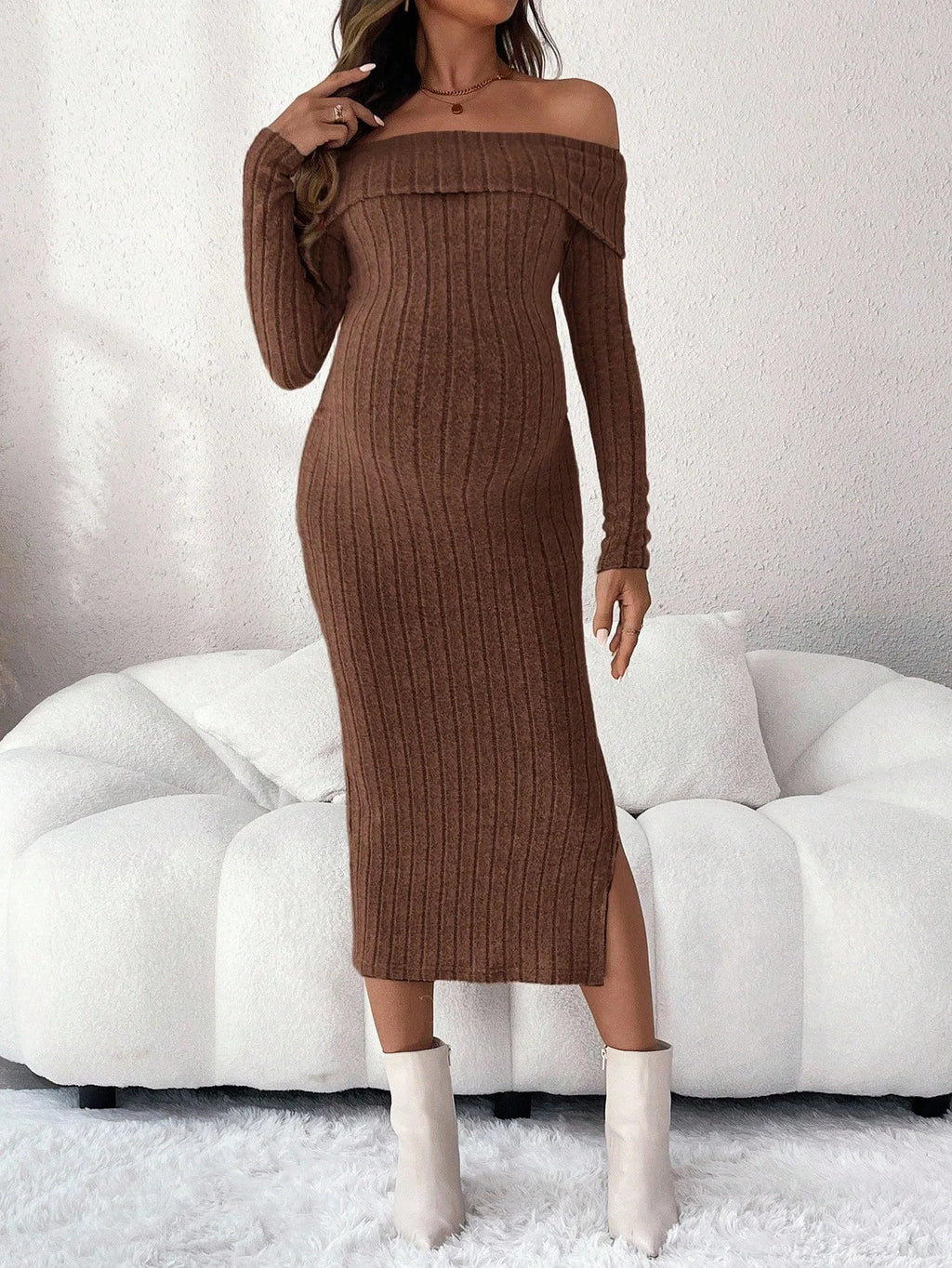 Brown off-the-shoulder ribbed knit midi dress with long sleeves and a side slit, worn with white ankle boots.