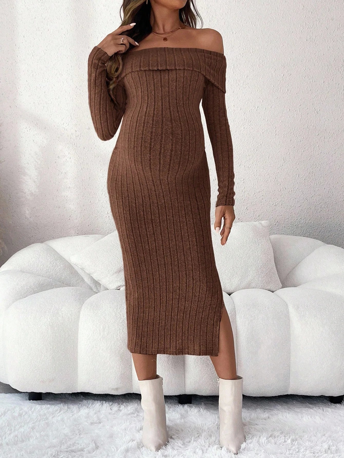 Brown off-the-shoulder ribbed knit midi dress with long sleeves and a side slit, worn with white ankle boots.