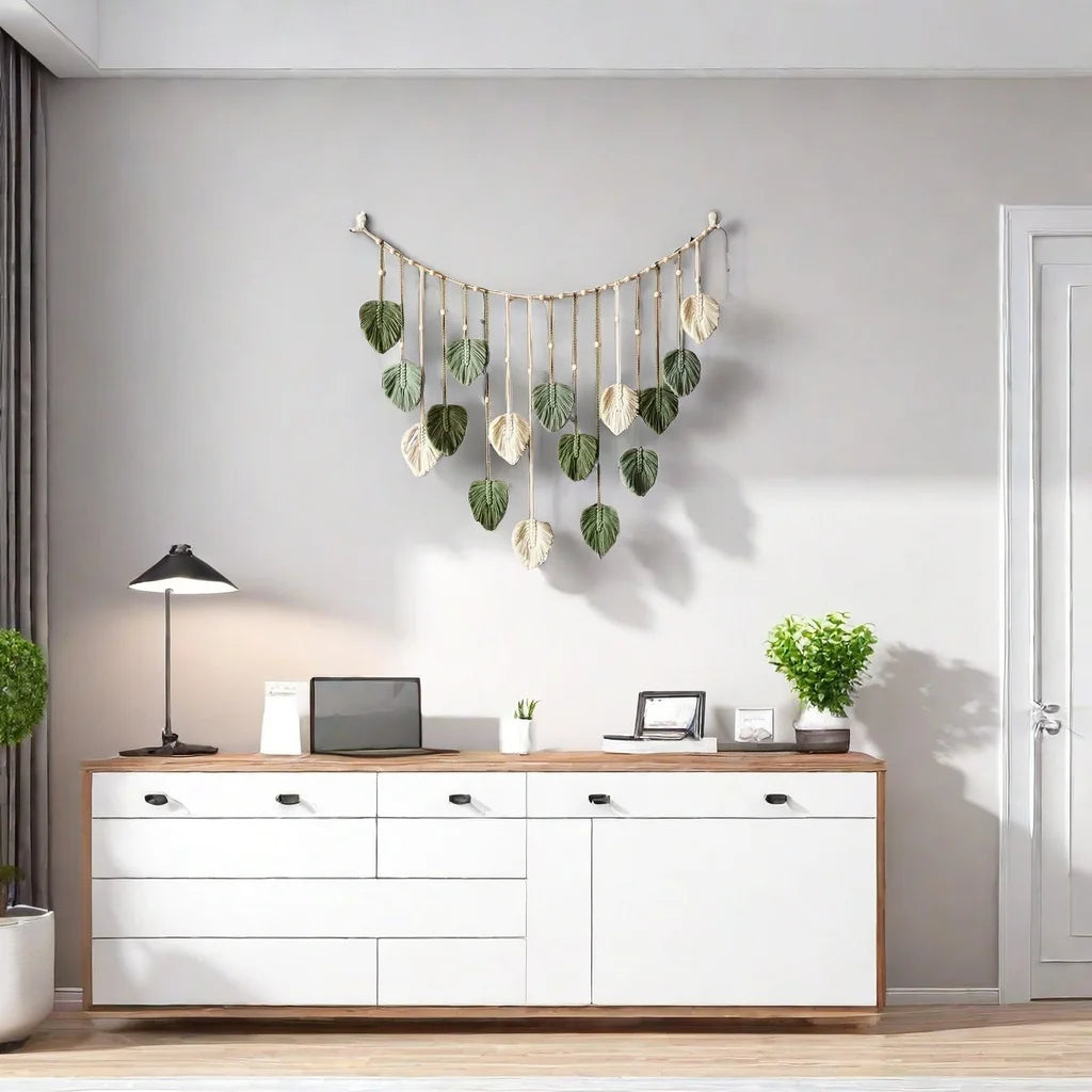 Boho-style macrame wall hanging featuring sage green and cream leaf-shaped tassels suspended from a curved wooden rod.