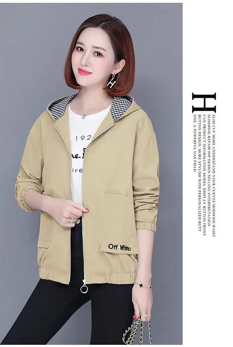 Woman wearing a beige, zip-up hooded jacket with a black and white gingham lining and front pockets.