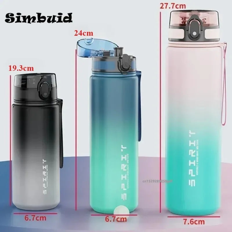Three ombre-coloured sports water bottles with flip lids and measurement labels in grey, blue, and pink.