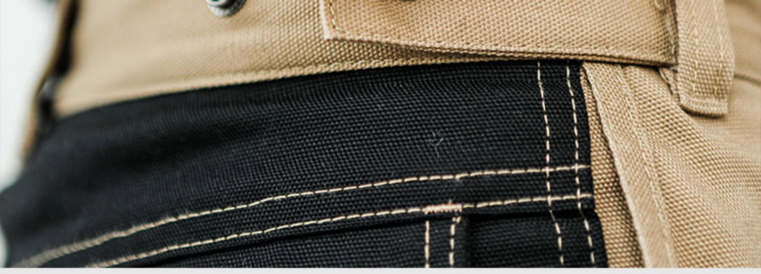 Close-up of beige and black cotton work trousers featuring durable heavy-duty stitching and multi-pocket cargo design.