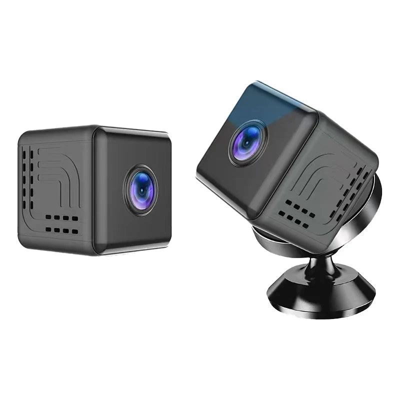 Two compact, black cube-shaped wireless indoor security cameras, one shown mounted on a small circular swivel stand.