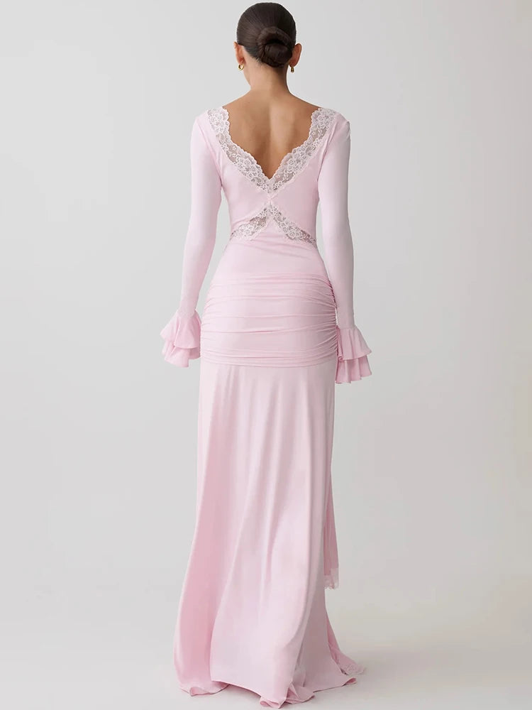 Pink bodycon maxi dress with long flare sleeves, white lace trim, and ruched back.