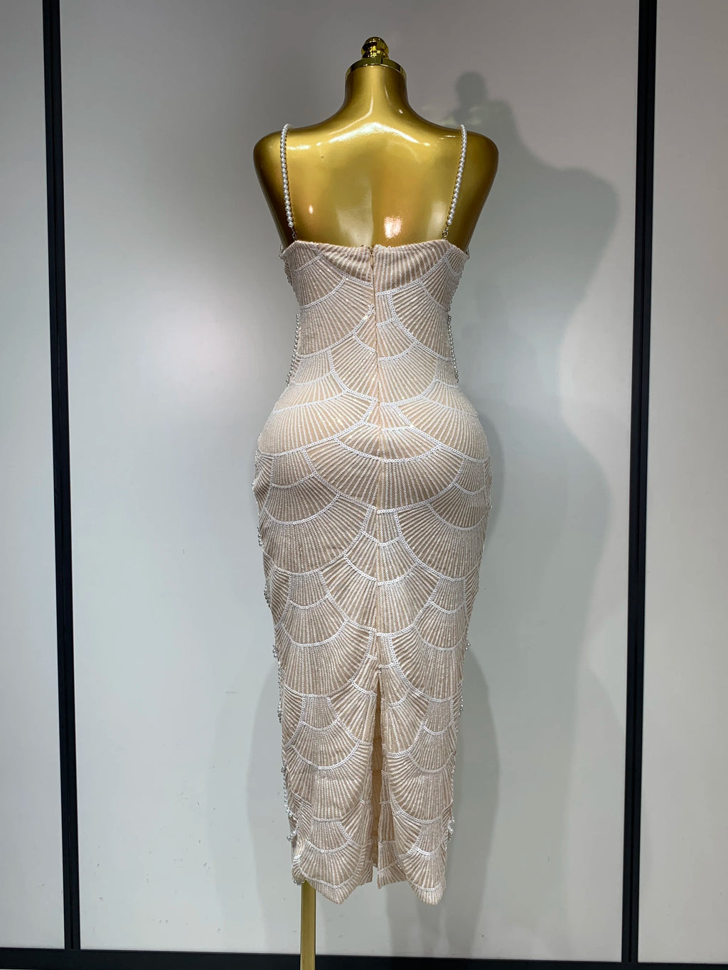 Beige bodycon maxi gown with pearl straps and white fan embroidery, displayed on a gold mannequin.