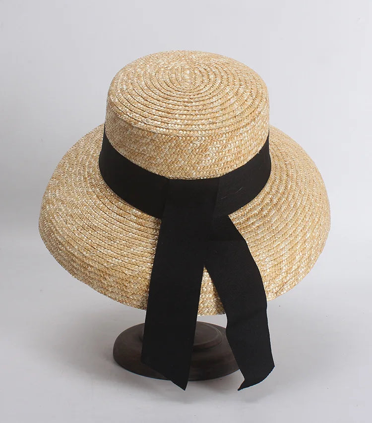 Elegant French-style straw sun hat with a wide brim and a black ribbon tied around the crown.