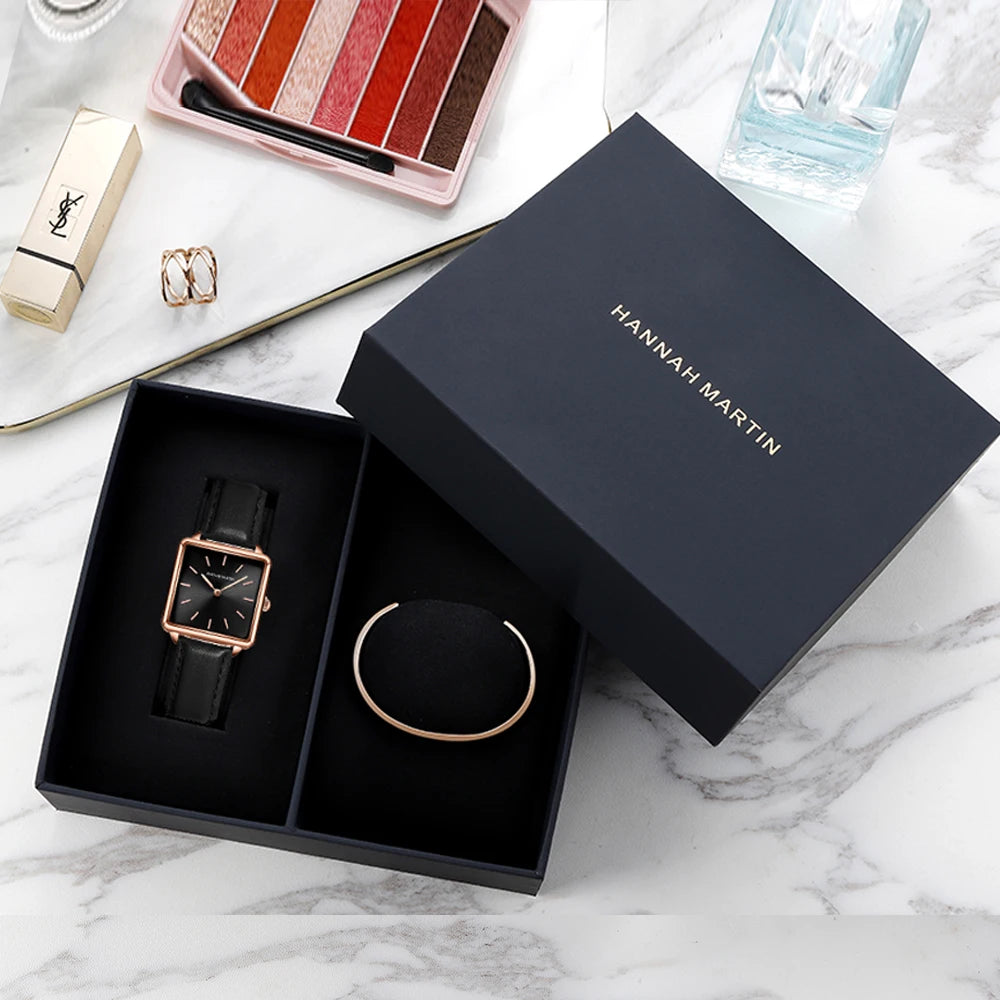 Black rectangular women's watch with rose gold case and black leather strap inside gift box.